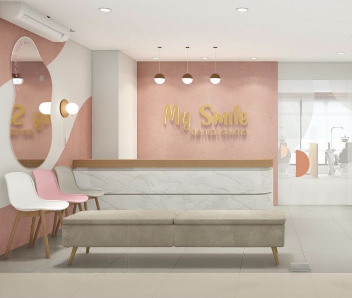 Reception at My Smile Dental Studio, with the gold logo sign on a pink wall